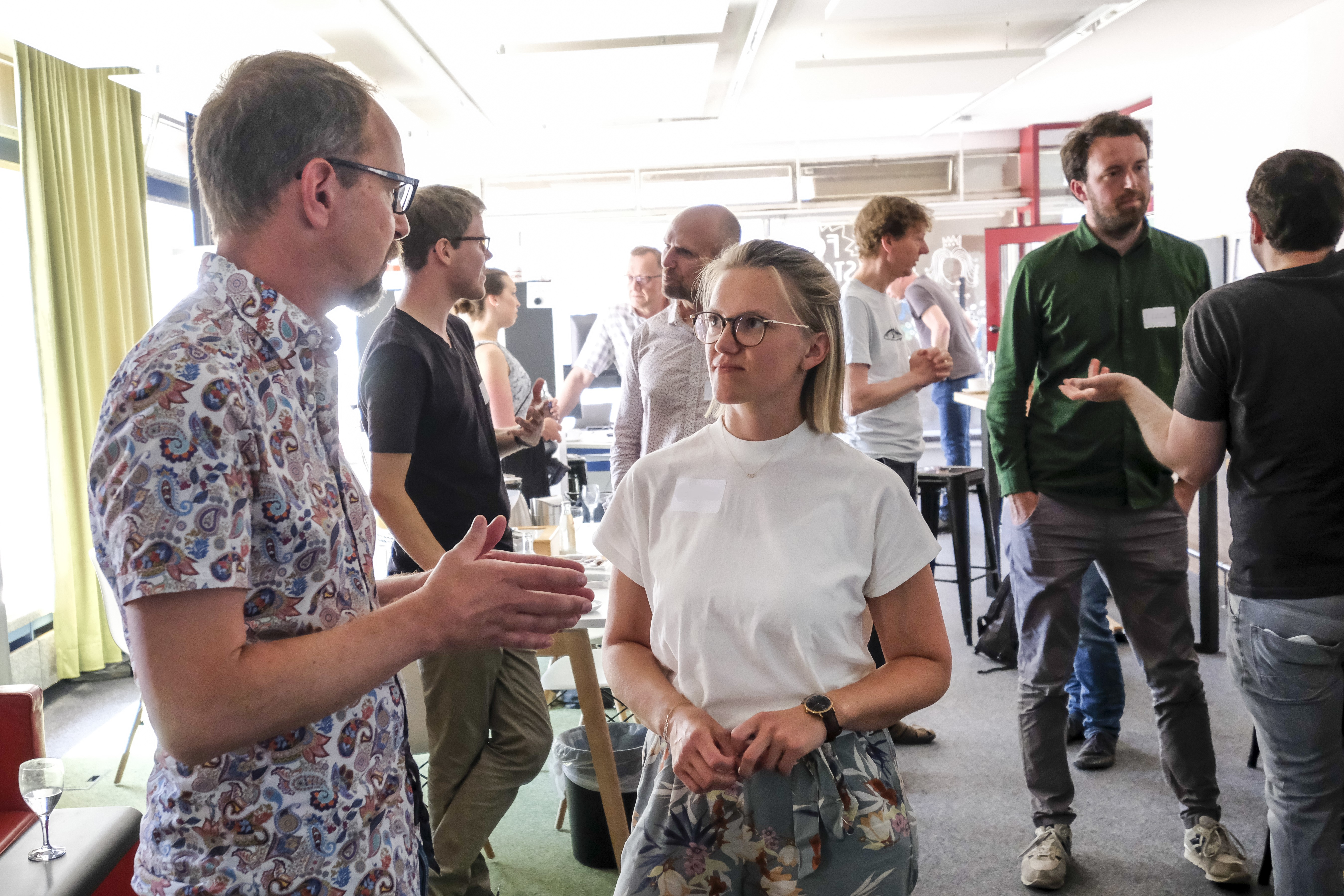 Zwei Personen im Vordergrund im Gespr&auml;ch und mehrere Gespr&auml;chspaare auch im Hintergrund